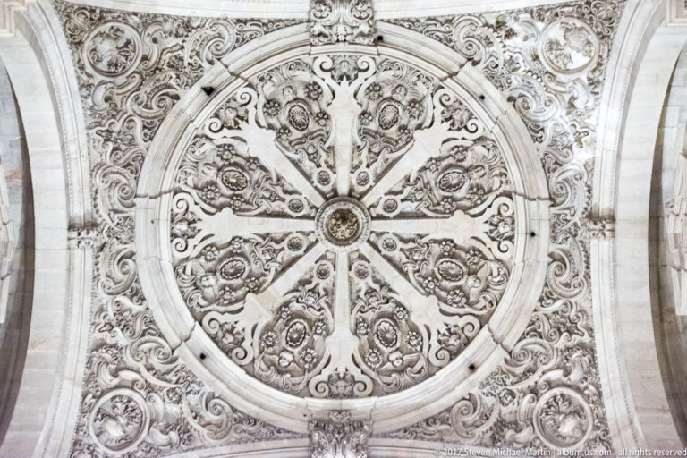 Eight-part circular relief ceiling with central medallion and dense symmetrical carving inside Granada Cathedral.