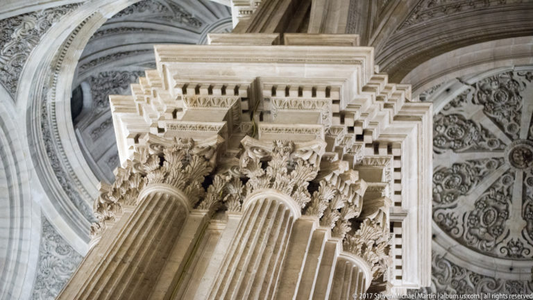 Low-angle close view of fluted columns, Corinthian capitals, and projecting entablature in Granada Cathedral.