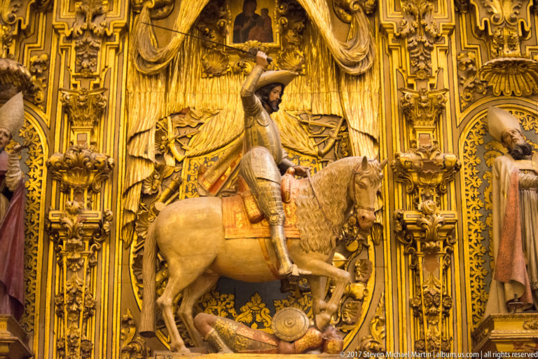 Polychrome Saint James the Greater riding a white horse within an elaborate gilded architectural setting.