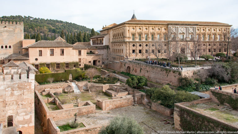Palace of Charles V rising above Alcazaba walls, archaeological remains, garden plots, and lower historic buildings.