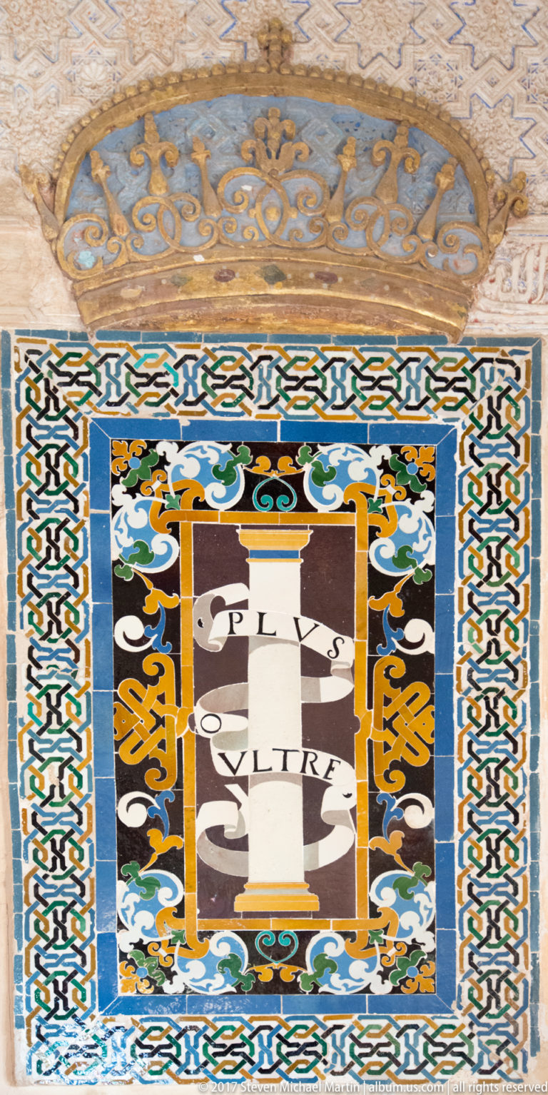 Square multicolored glazed-tile panel with a central shield-like emblem, scrolling ornament, and interlaced border.