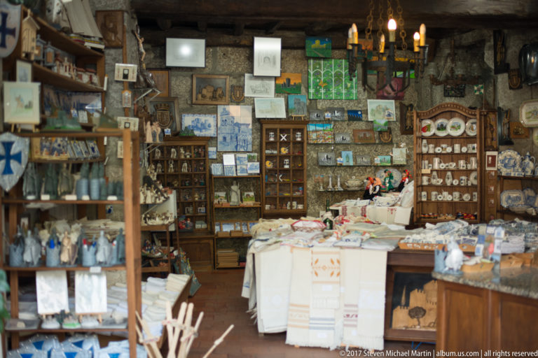 Small shop densely filled with religious figurines, framed sacred images, textiles, ceramics, and devotional souvenirs.