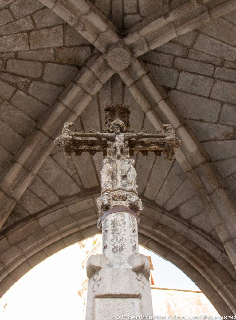 Weathered carved stone cross rising beneath the ribbed Gothic vault of the Padrão do Salado monument.