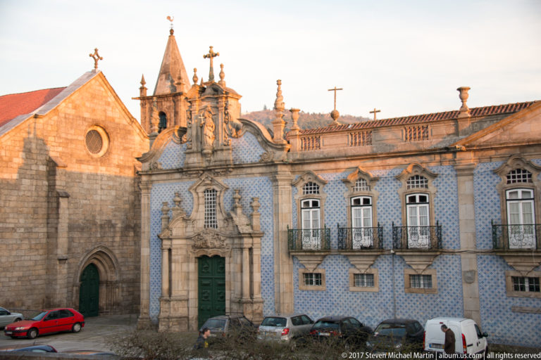 Granite Gothic Church of São Francisco beside a blue-and-white tiled Baroque façade with ornate stone portal and green doors.