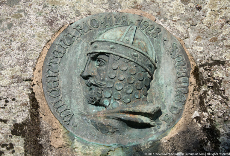 Round green-patinated bronze medallion set into granite, showing helmeted Afonso Henriques in profile within a raised inscription.