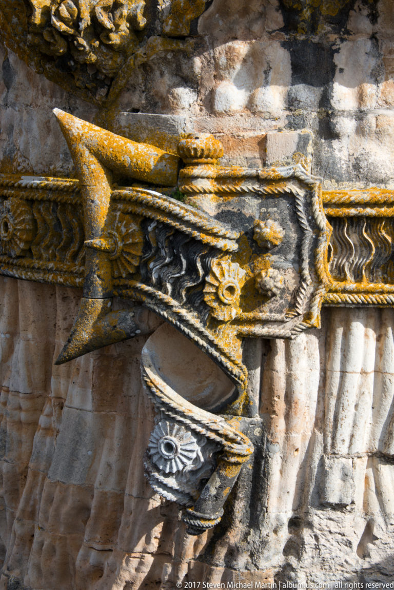 Close-up of weathered Manueline stone carving with rope-like bands, ridges, and projecting ornamental forms.