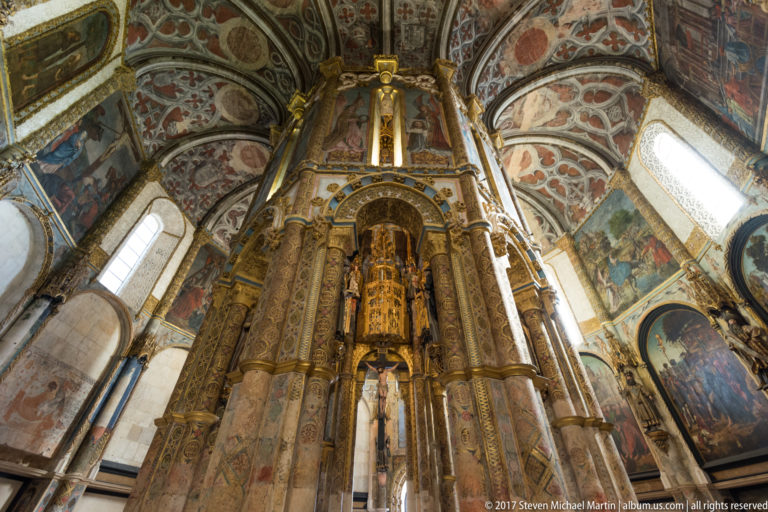 Tall central core of the Charola with clustered columns, gilded panels, painted niches, murals, and bright perimeter windows.