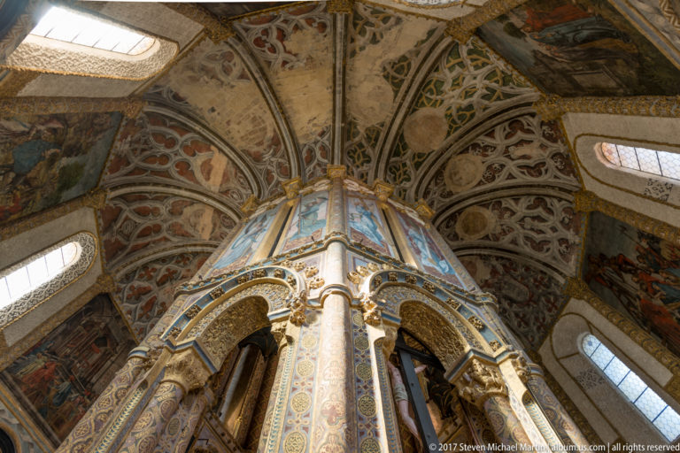 Upward view of the Charola’s tall central octagonal core surrounded by painted vaults, gilded details, columns, murals, and high windows.