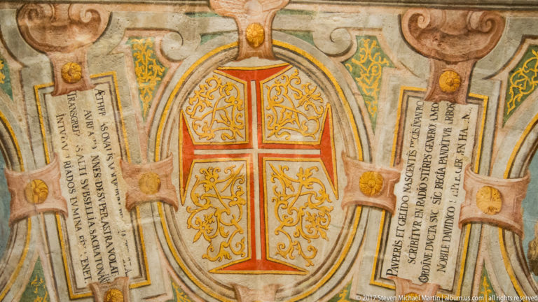 Painted ceiling panel with a red Order of Christ cross, gilded scrollwork, and flanking Latin inscriptions.