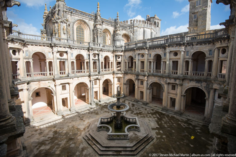 Two-story Renaissance Cloister of John III surrounding a central octagonal fountain, seen from an upper gallery.