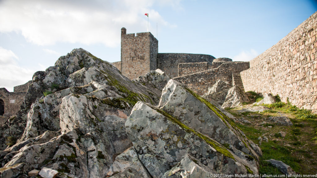 Jagged lichen-covered rocks lead toward Marvão Castle’s square keep and long stone curtain wall.