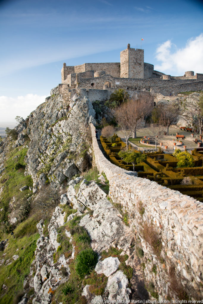 Marvão Castle on a rocky ridge above a stone approach wall and clipped formal garden.