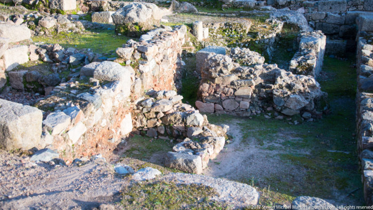 Excavated stone and brick wall foundations form small rooms and passages viewed from above.