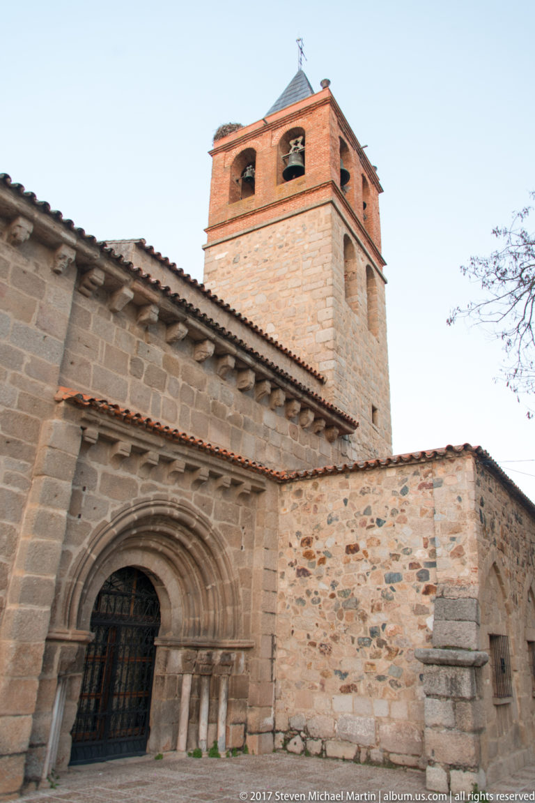 Angled exterior view of the Basilica of Santa Eulalia with arched stone portal and square bell tower.