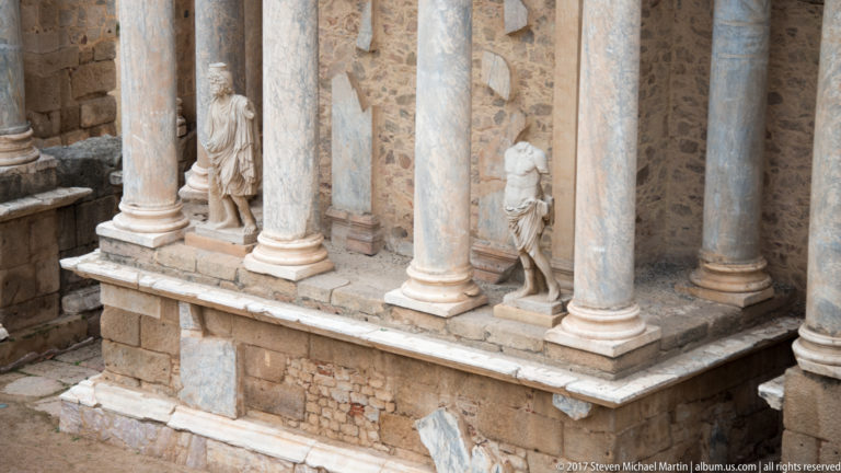 Close view of marble columns and standing statues arranged on the stage façade of Mérida's Roman Theatre.