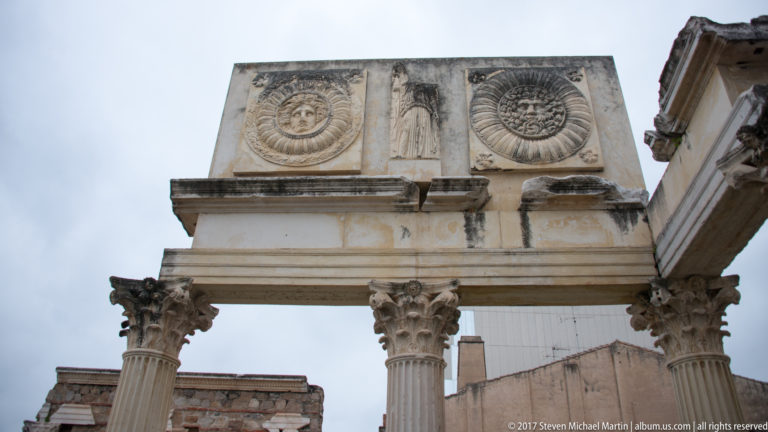 Two carved circular reliefs above fluted Corinthian columns in the reconstructed Portico del Foro at Mérida.