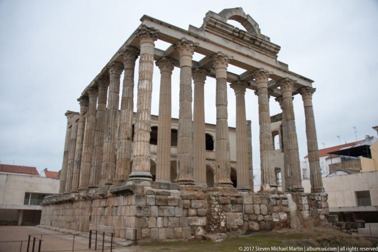 Low-angle view of Mérida's Temple of Diana with tall fluted Corinthian columns on a massive stone podium.