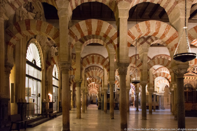 Long interior aisle of stone columns and red-and-white striped double arches inside the Mezquita.