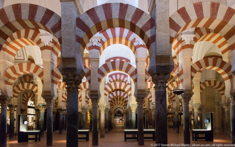 Symmetrical view through dense rows of columns and red-and-light striped double arches in the Mezquita.