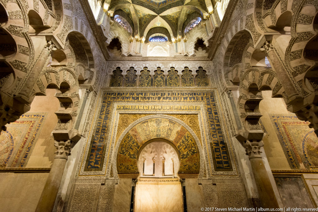Mihrab framed by intersecting multilobed arches, Arabic inscriptions, and richly patterned vaulting in the Mezquita.