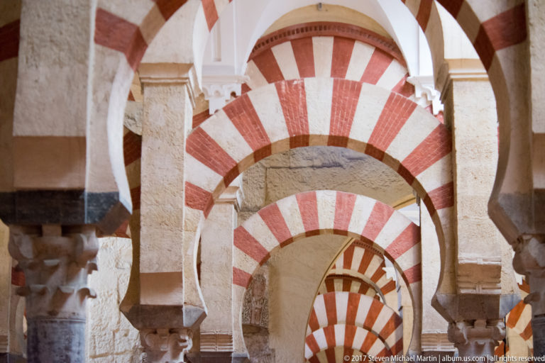 Compressed view of nested red-and-light arches and stone supports repeating deep into the Mezquita interior.