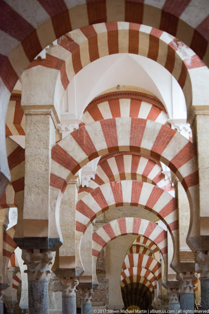 Close study of layered red-and-light arches, squared piers, and carved capitals in the Mezquita.