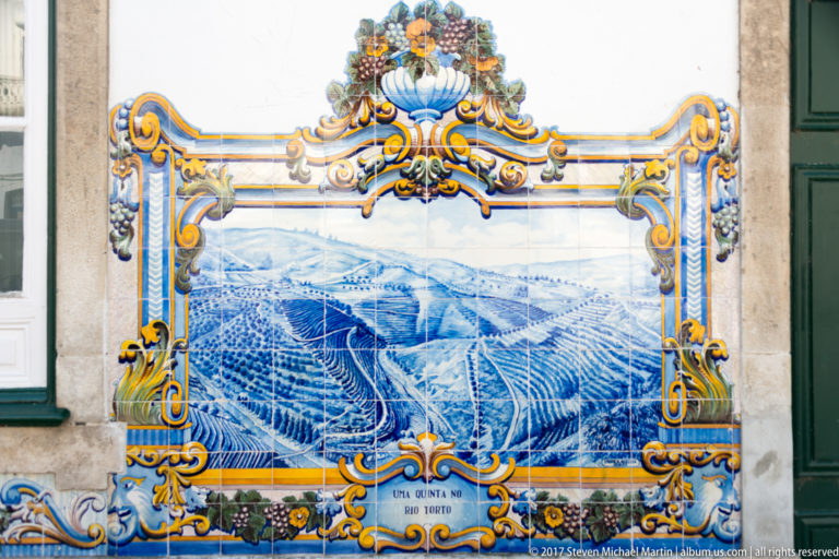 Blue-and-white azulejo mural labeled Uma Quinta no Douro, depicting a large terraced wine estate beneath an ornate floral frame.