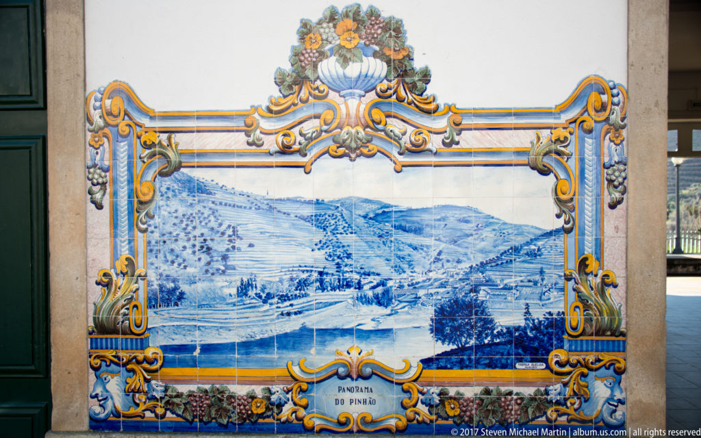 Blue-and-white azulejo panorama labeled Panorama do Pinhão, showing the river, hills, and settlement within an ornate frame.