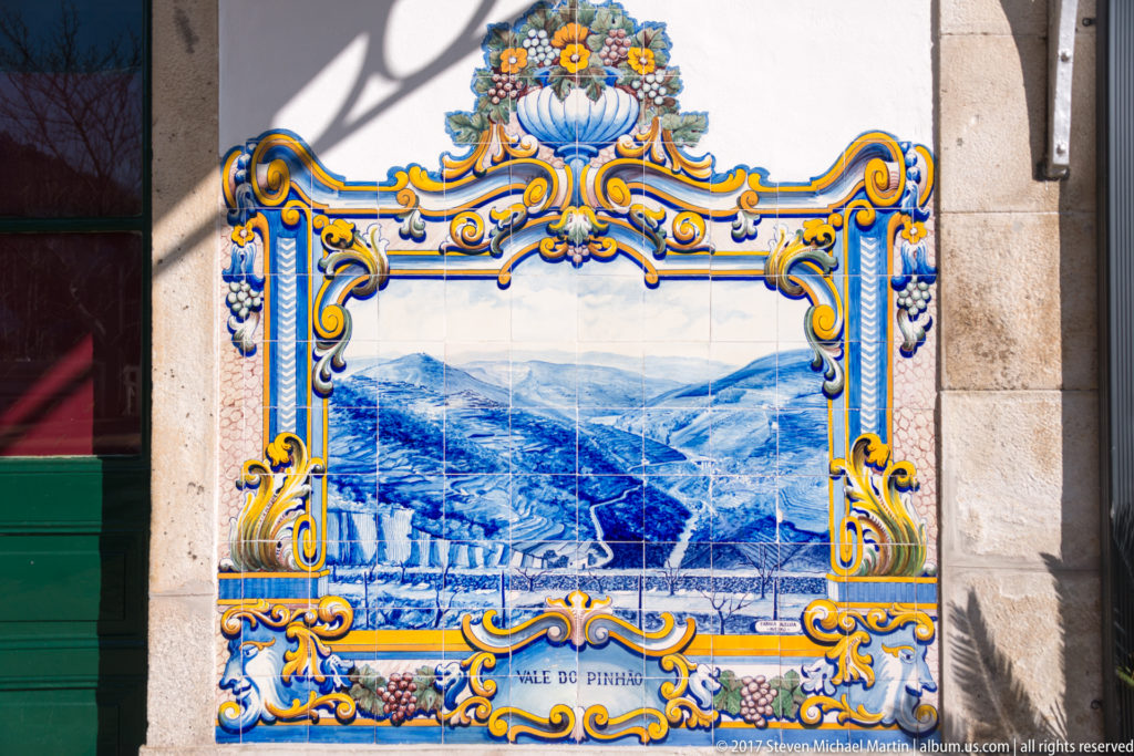 Blue-and-white Vale do Pinhão azulejo showing terraced hills descending into a narrow cultivated valley.