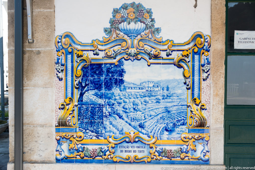 Azulejo panel labeled Estação Vitivinícola do Douro no Torto, showing a large building above terraced cultivated slopes.