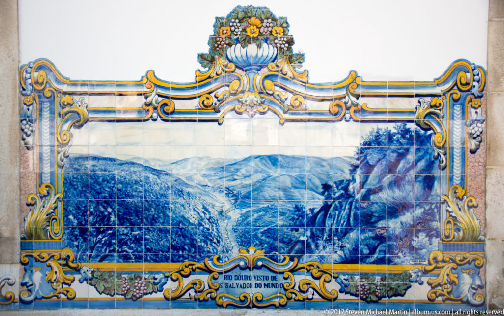 Wide azulejo labeled Rio Douro visto do Salvador do Mundo, showing the Douro amid layered mountain ridges from a high viewpoint.