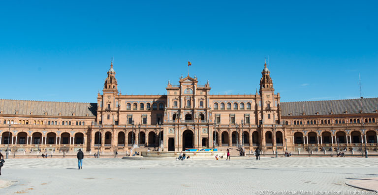 Wide frontal view of Plaza de España showing the central pavilion, twin towers, long arcades, and open plaza.