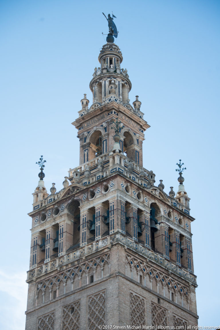Ornate multistory tower with arcades, columns, balustrades, decorative panels, and an equestrian figure at the summit.