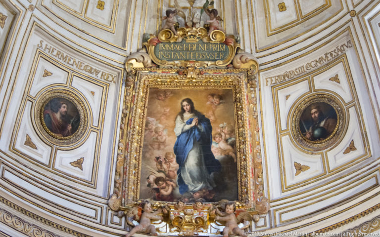 Immaculate Conception painting in a gilded frame, flanked by oval portraits and Latin inscriptions in an ornate interior.