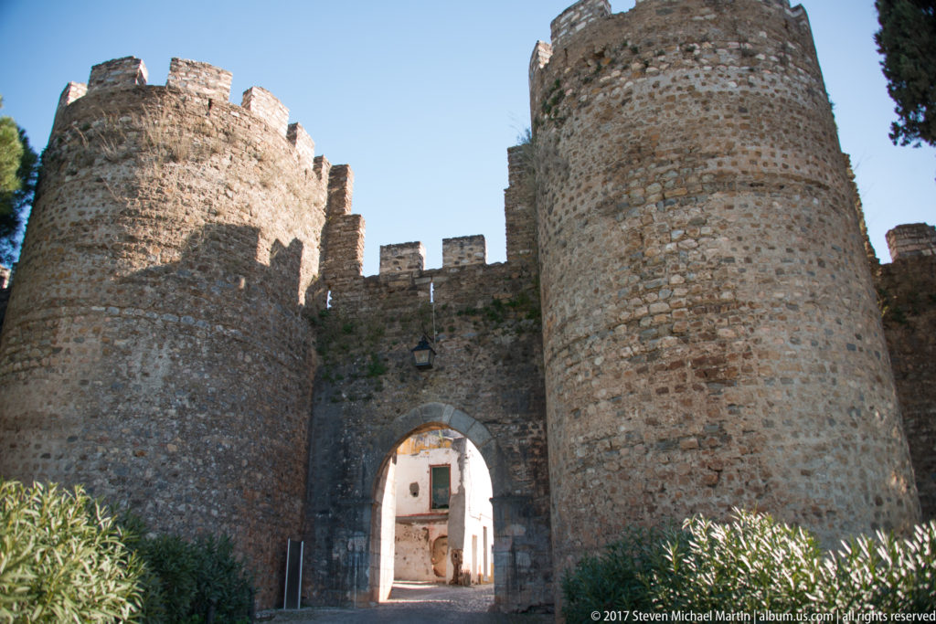 Arched passage between two massive round stone towers with crenellated tops at Vila Viçosa Castle.