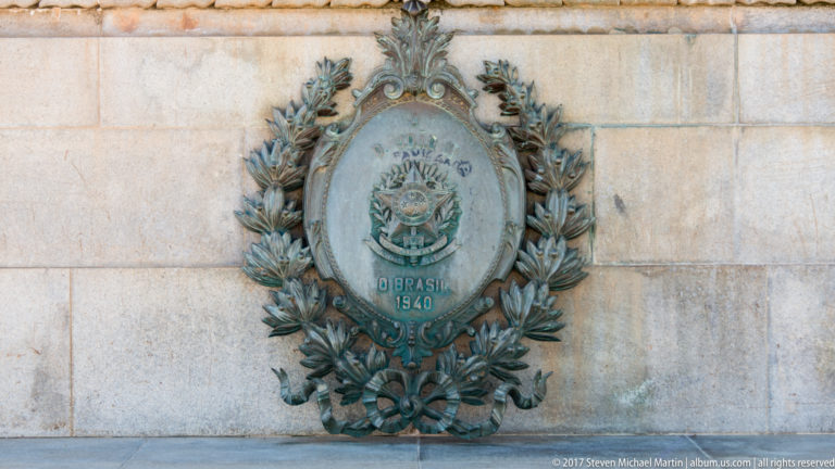 Bronze oval commemorative plaque reading “O BRASIL 1940,” surrounded by a sculpted wreath on pale stone.