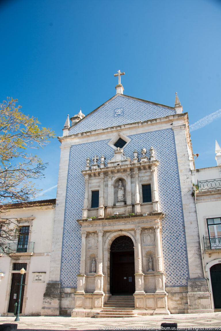 Igreja da Misericórdia façade with blue-and-white azulejos and a monumental carved limestone portal framed by Corinthian columns and statues.