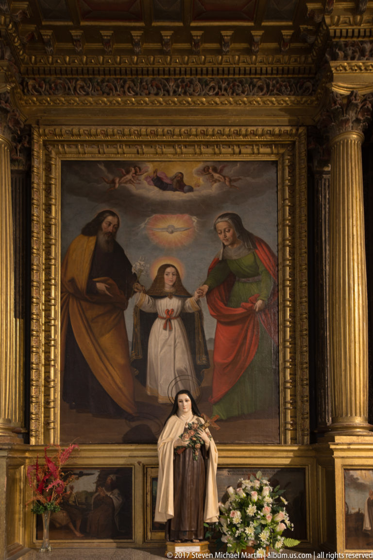 Large gilded altar framing a devotional painting centered on a young female figure in the Saint Teresa complex.