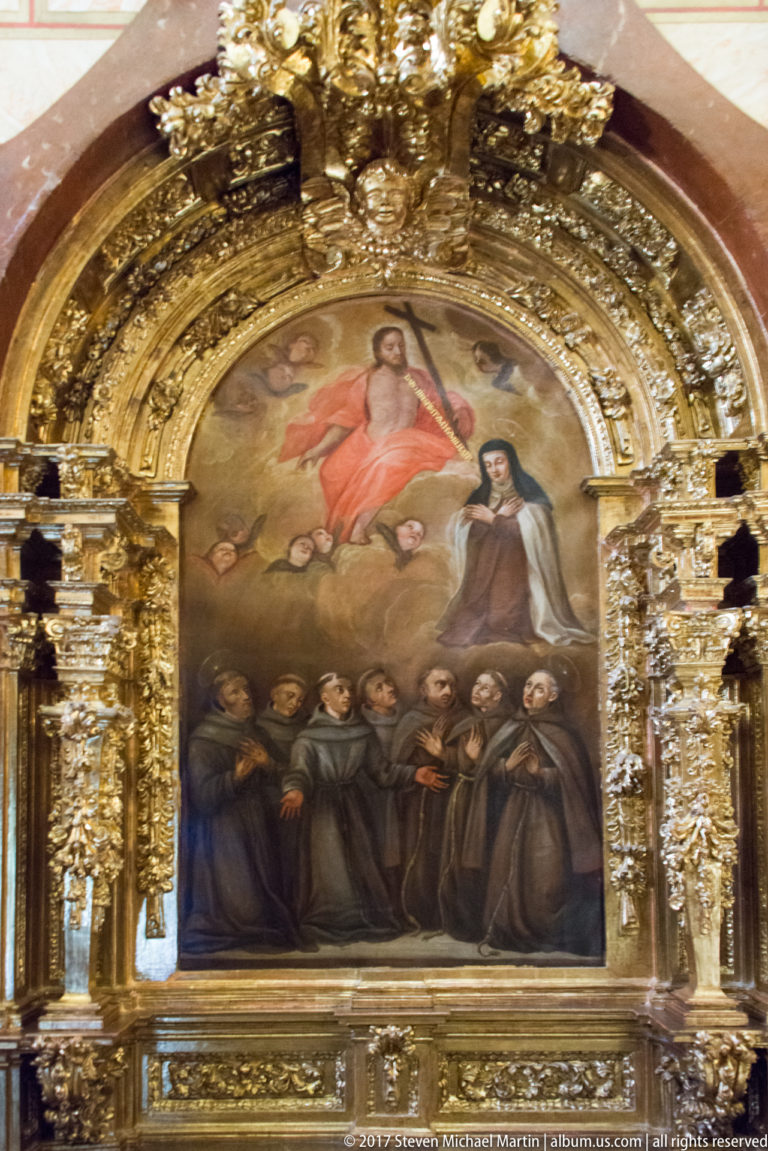 Gilded altar painting showing Christ above a group of kneeling friars in dark robes.