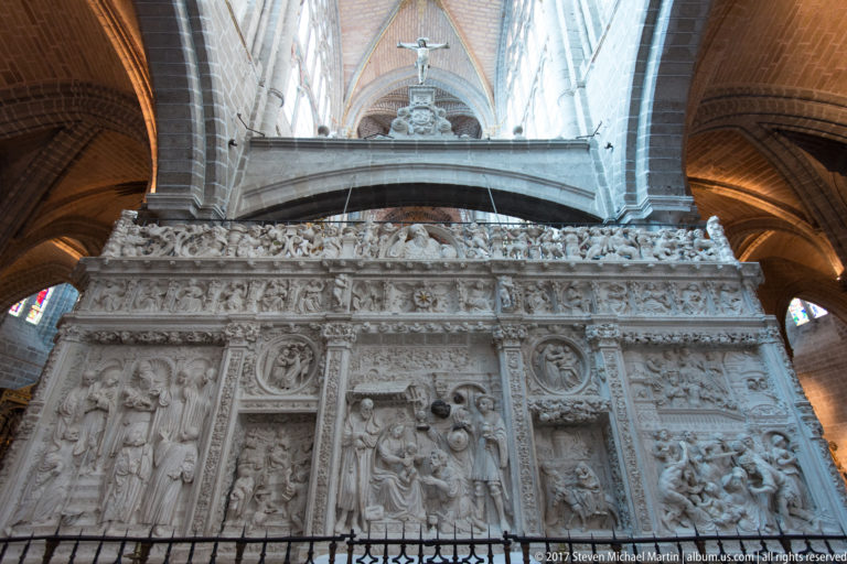 Close view of carved biblical relief panels and dense Plateresque ornament on the retrochoir of Ávila Cathedral.