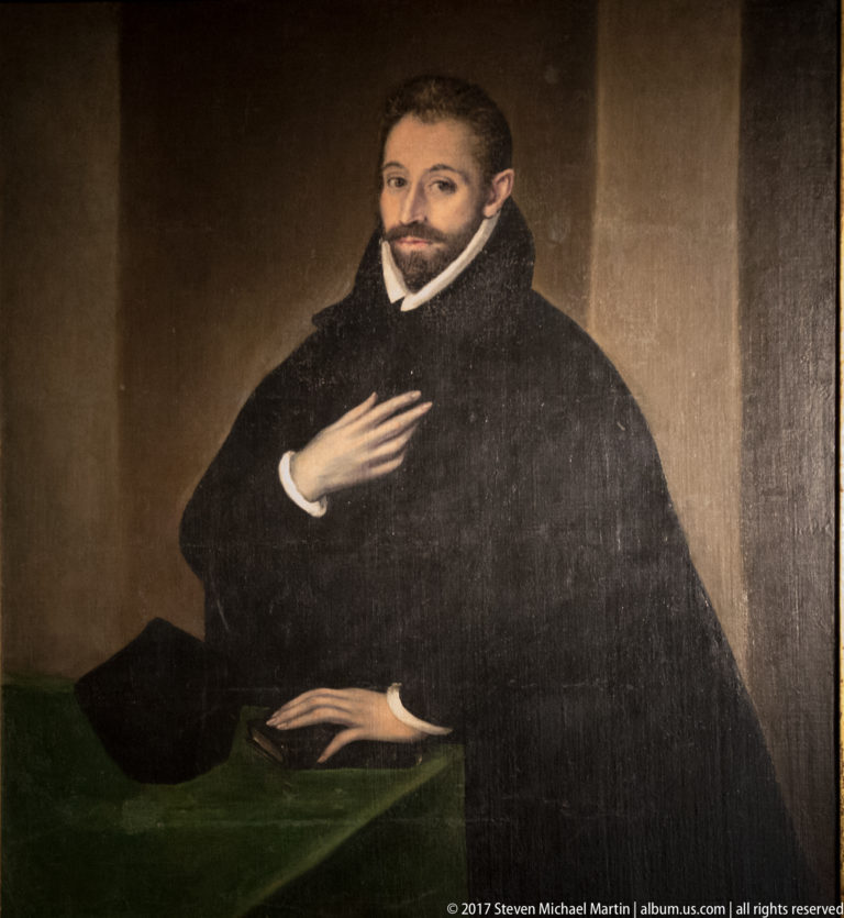 Formal portrait of a bearded cleric in dark robes and a white collar against a plain brown background.
