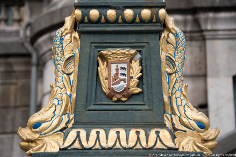 Dark-green and gilded ornamental lamp base bearing Bilbao’s civic shield, with stylized golden decorative creatures.
