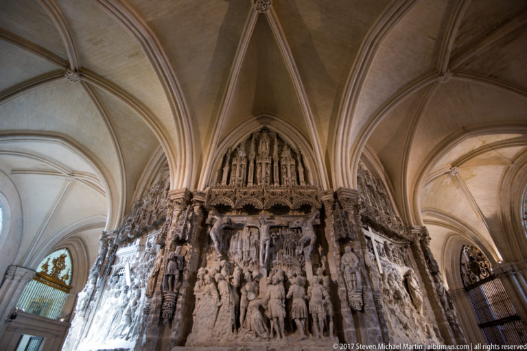 Large pale-stone religious relief packed with carved figures beneath ribbed Gothic vaults.