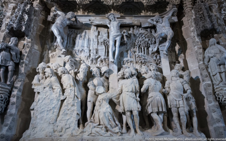 Close view of a carved Crucifixion relief with Christ above crowded groups of mourners and soldiers.