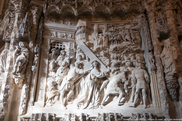 Large pale-stone biblical relief with a central robed figure surrounded by densely carved attendants.