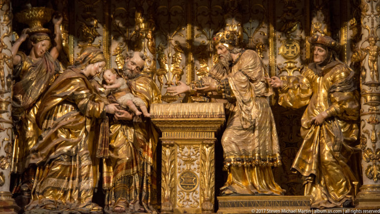 Gilded biblical relief with the infant Christ presented to an elderly priest across an altar, surrounded by attendants.