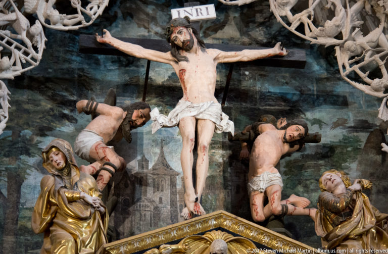 Polychrome Crucifixion group with Christ on the cross, attendant figures, gilded drapery, and additional suffering bodies.