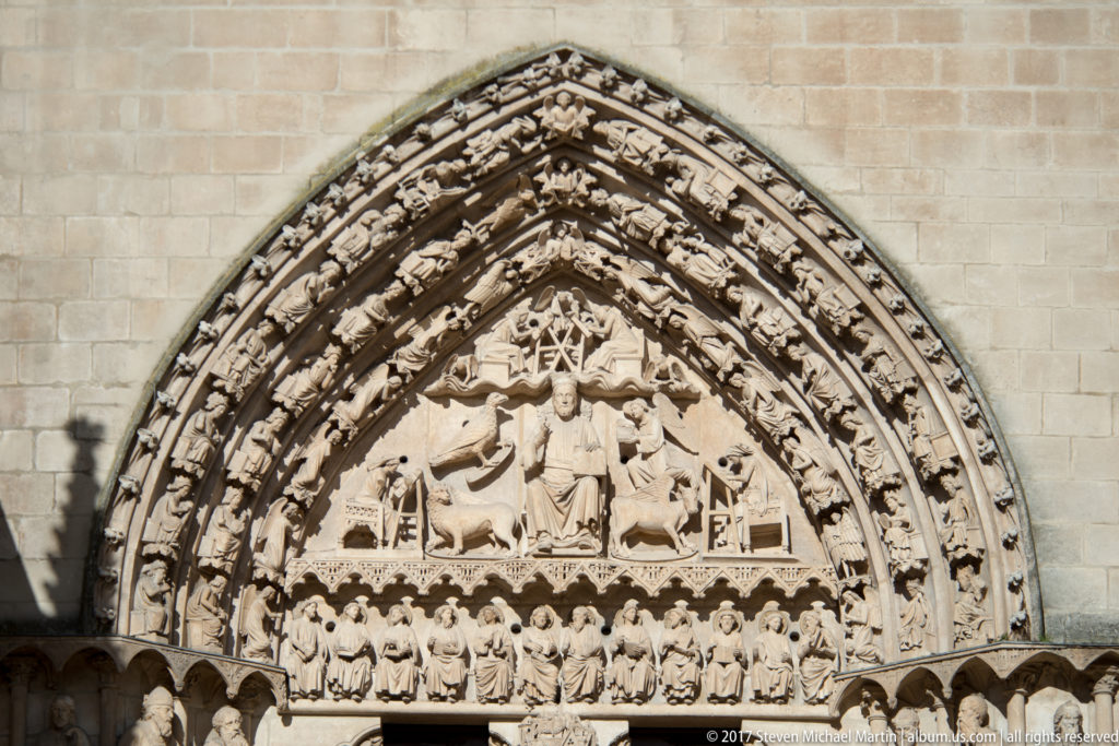 Gothic tympanum and archivolts of the Puerta del Sarmental, with Christ in Majesty above rows of carved figures.