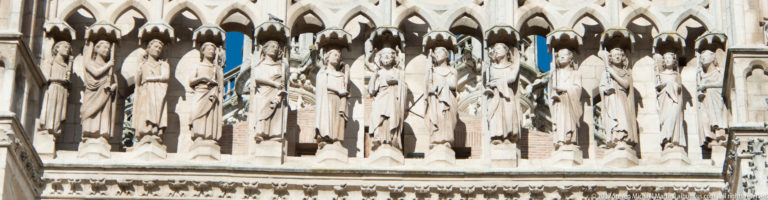 Row of standing stone saints beneath pointed Gothic canopies on the exterior of Burgos Cathedral.