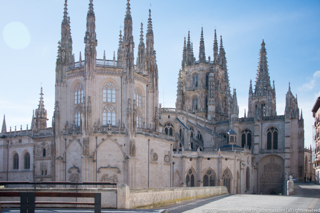 Burgos Cathedral exterior with clustered Gothic pinnacles, towers, large traceried windows, and pale stone chapels.